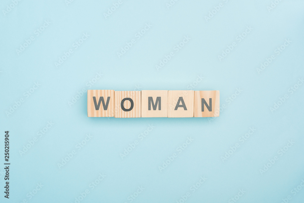 top view of woman lettering made of wooden cubes on blue background top view of woman lettering made of wooden cubes on blue background