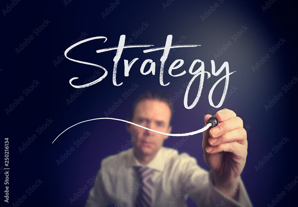A businessman writing a Strategy concept with a white pen on a clear screen. A businessman writing a Strategy concept with a white pen on a clear screen.