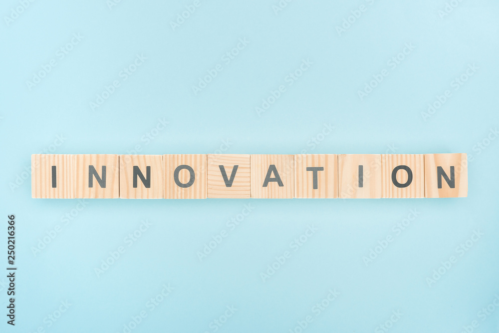 top view of innovation lettering made of wooden cubes on blue background top view of innovation lettering made of wooden cubes on blue background