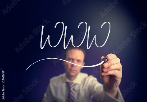 A businessman writing a WWW concept with a white pen on a clear screen.
