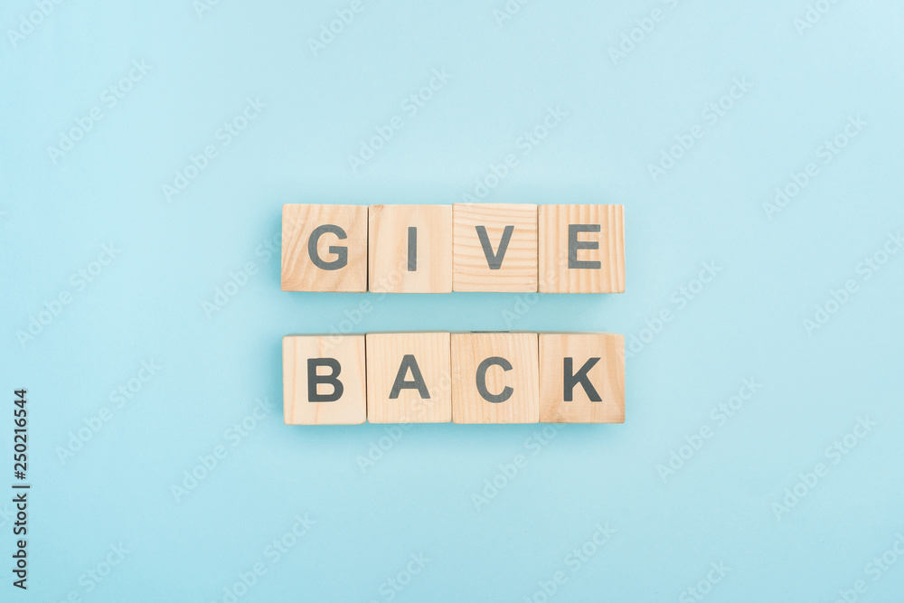top view of give back lettering made of wooden cubes on blue background