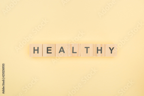 top view of healthy lettering made of wooden cubes on yellow background