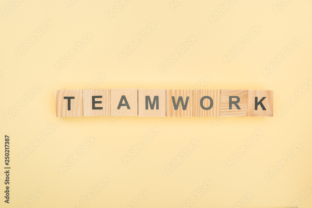 top view of team work lettering arranged of wooden blocks on yellow background top view of team work lettering arranged of wooden blocks on yellow background