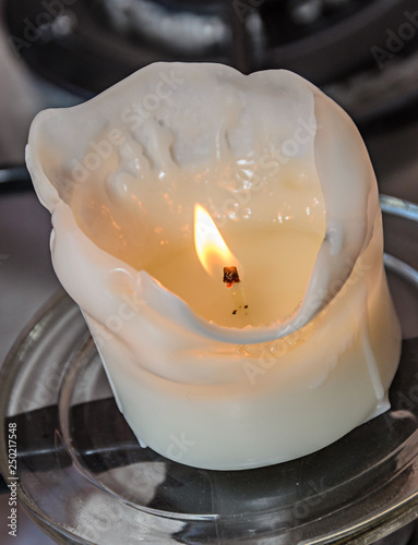 Burning white candle, melted wax, close up flame photo