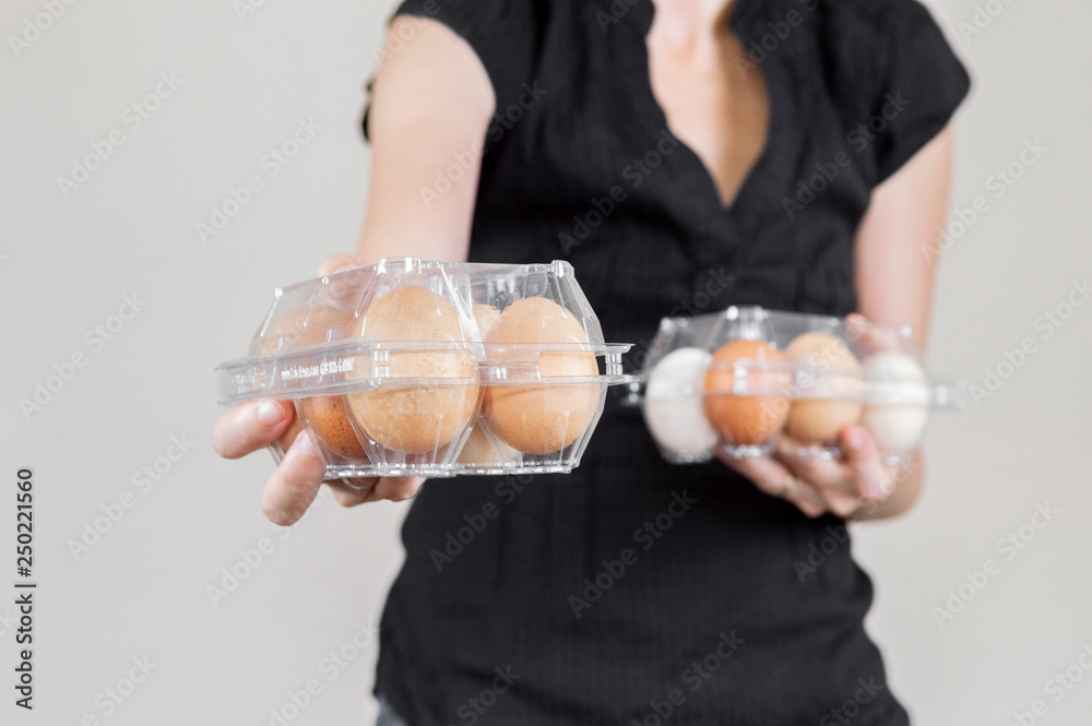 Caucasian woman with black shirt holding two plastic egg boxes full of chicken eggs Caucasian woman with black shirt holding two plastic egg boxes full of chicken eggs