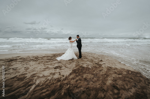 The bride and groom are walking along the beach. Panoramic view.