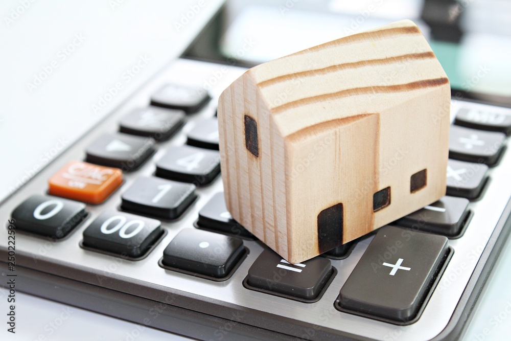 Business, finance, savings, money management, property loan or mortgage concept : Wood house model on calculator Business, finance, savings, money management, property loan or mortgage concept : Wood house model on calculator