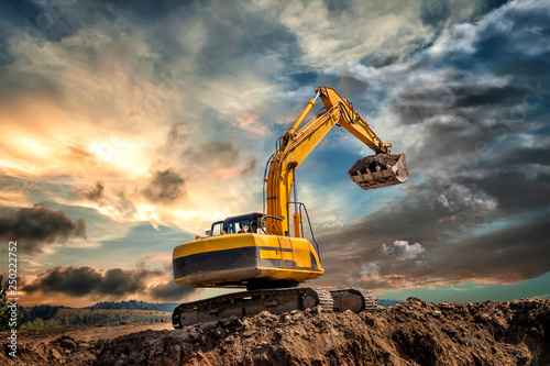 Obraz na plátně Crawler excavator during earthmoving works on construction site at sunset