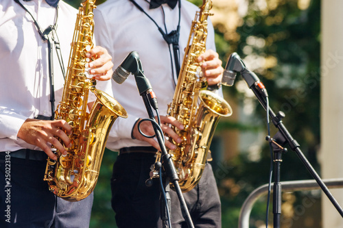 two saxophonists playing at a jazz festival in a city park photo