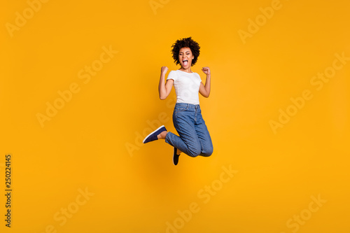 Full length body size side profile photo jumping high beautiful she her lady yelling loud voice hands arms up win wearing casual jeans denim white t-shirt clothes isolated yellow bright background photo