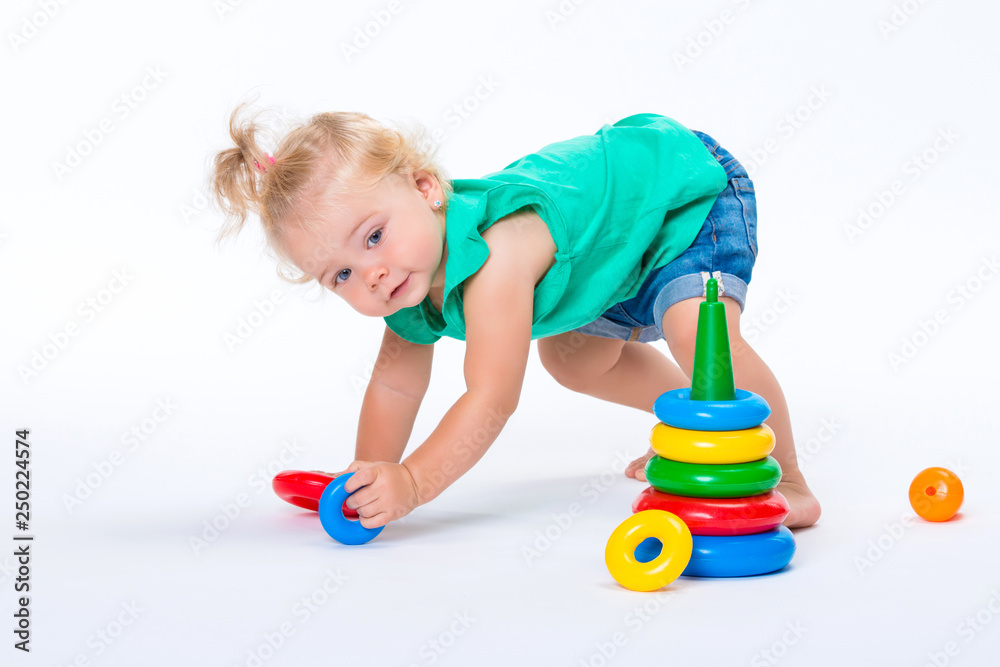 Cute kid blonde girl playing with color pyramid toy isolated on white background. Happy childhood and pre-school development of children Cute kid blonde girl playing with color pyramid toy isolated on white background. Happy childhood and pre-school development of children