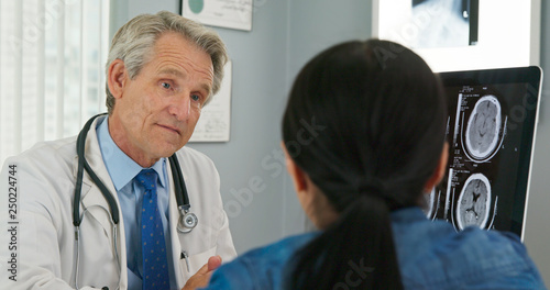 Doctor and patient having discussion about health care options in medical office. Male Caucasian physician talking with woman in hospital
