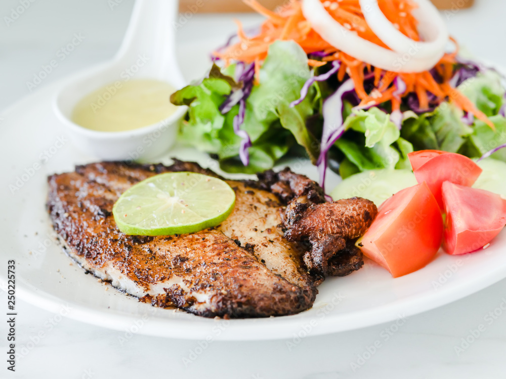 Grilled fish steak with salad with white plate on marble table. Grilled fish steak with salad with white plate on marble table.