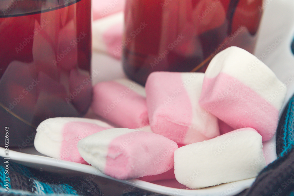 White-pink marshmallow on a plate with two cups of tea