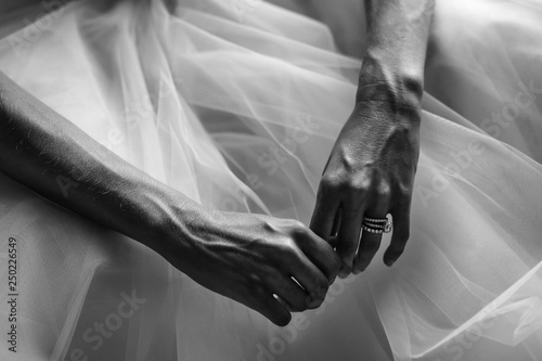 Black and white picture of bride with delicate hands holding them on her dress