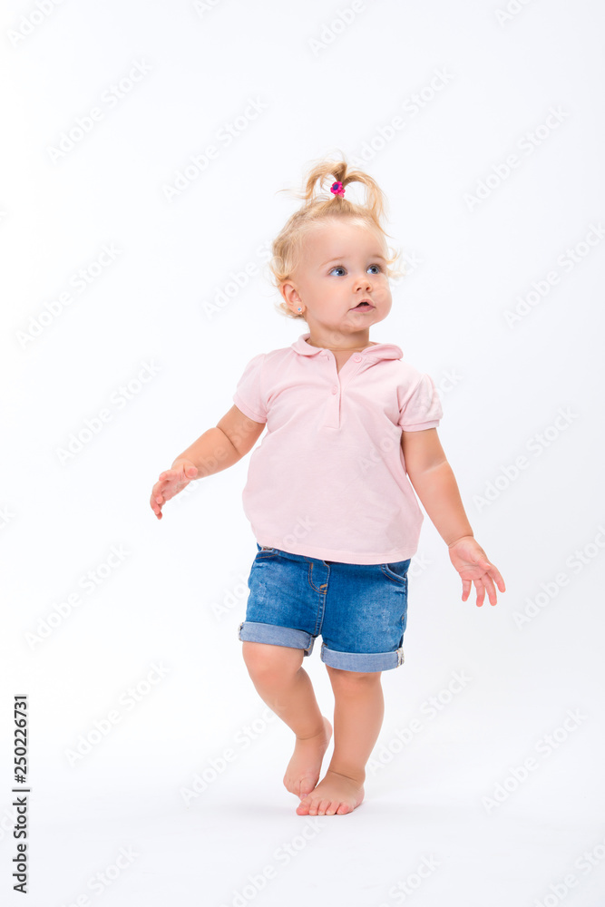 Cute little child baby girl learns to walk, make first steps isolated on a white background Cute little child baby girl learns to walk, make first steps isolated on a white background