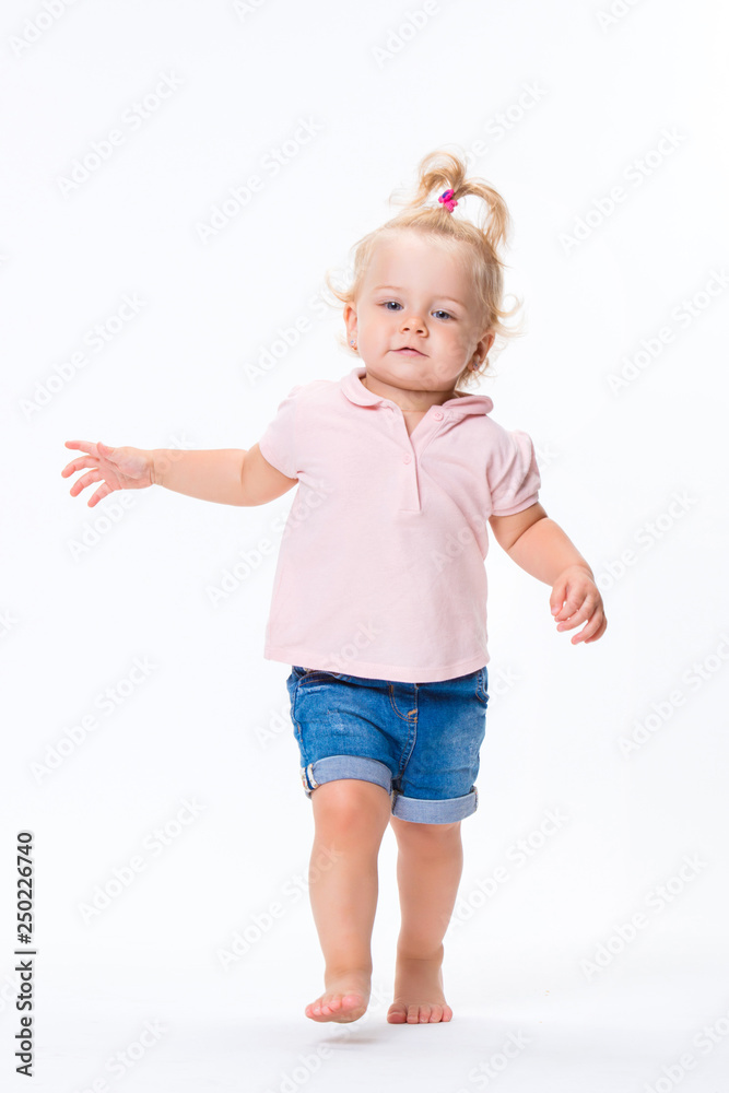 Cute little child baby girl learns to walk, make first steps isolated on a white background Cute little child baby girl learns to walk, make first steps isolated on a white background