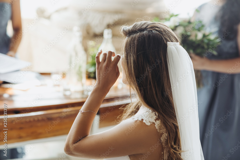 Fototapeta premium Look from behind at charming bride touching her eyes