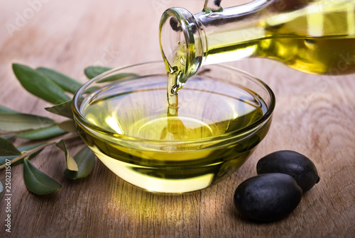Quadro su tela Bowl with olive oil on wooden table