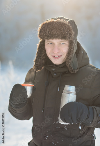 A man with a thermos and a cup of tea in winter