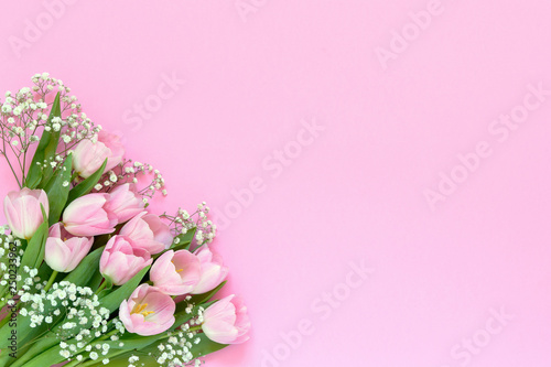 Bouquet of pink tulips and gypsophila flowers on pink background. Top view, copy space.