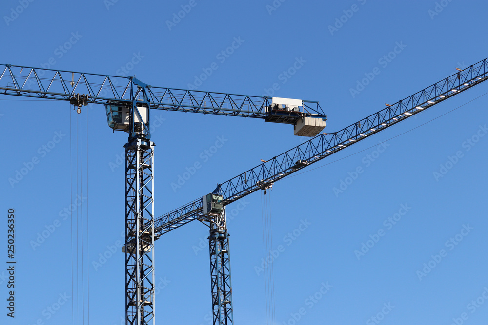 Construction cranes on background of clear blue sky