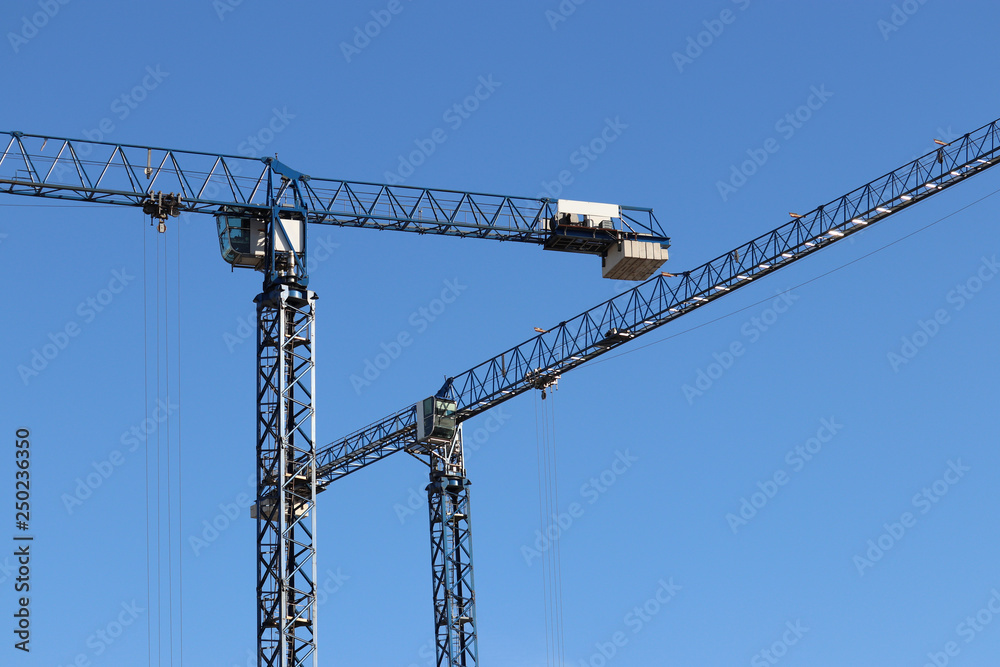 Construction cranes on background of clear blue sky Construction cranes on background of clear blue sky