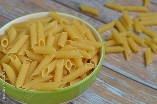 The​ Penne​ Rigate​ raw​ in​ a​ bowl​ on​ the​ table