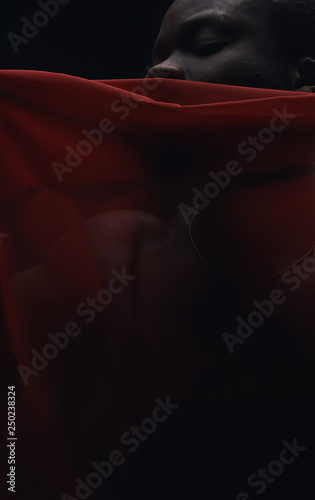 Art portrait of black man posing behind red fabric. Sensual. Art performance, acting. Dark key