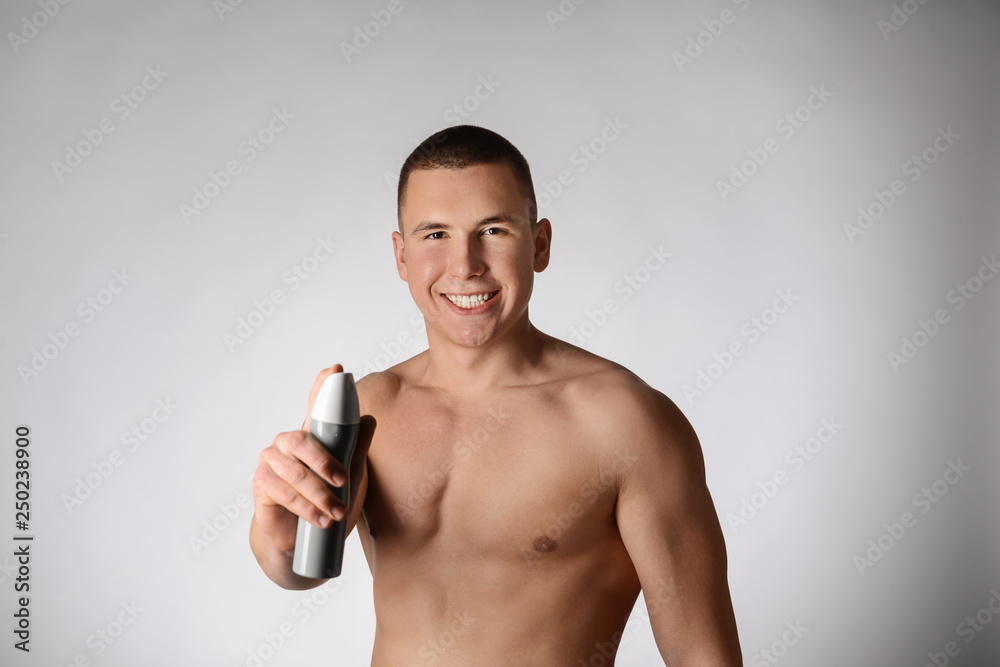 Handsome young man with deodorant on grey background Handsome young man with deodorant on grey background