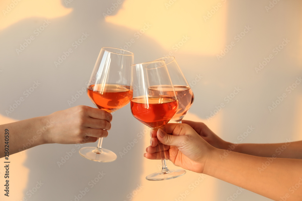 Women clinking glasses with tasty wine on light background Women clinking glasses with tasty wine on light background