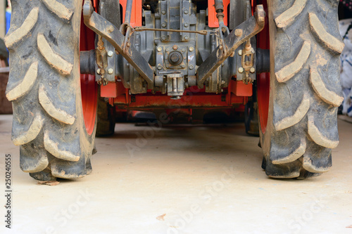the behind of orange tractor with big tyre and metal peripheral kit