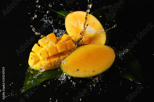 Obraz na płótnie Ripe cut mango with water splash on dark background