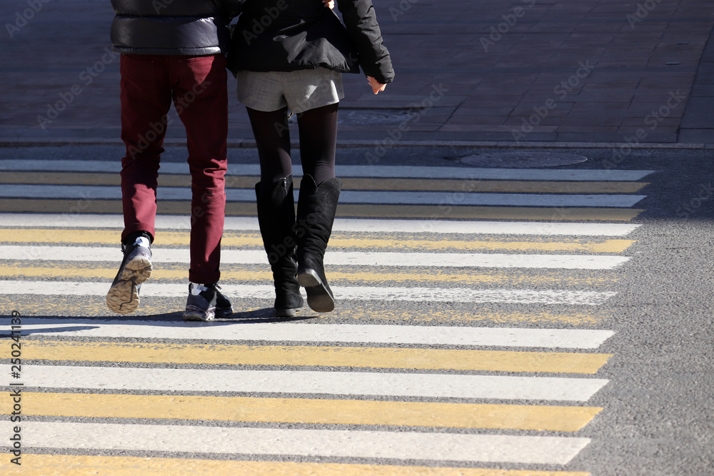 Couple walking on pedestrian crossing, rear view. Male and female feet on the crosswalk, people on the street, safety concept Couple walking on pedestrian crossing, rear view. Male and female feet on the crosswalk, people on the street, safety concept