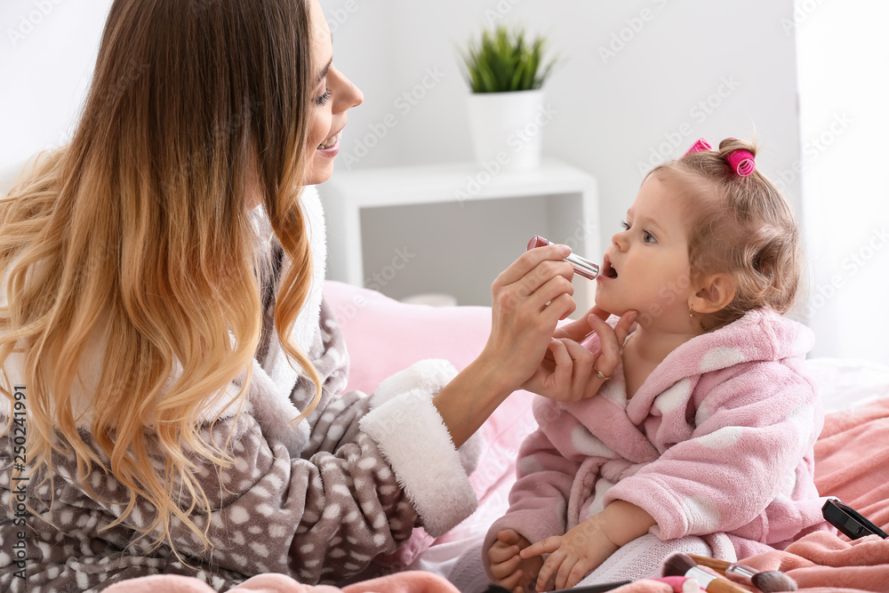 Young woman with her cute little daughter playing with cosmetics at home Young woman with her cute little daughter playing with cosmetics at home