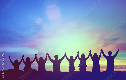 Silhouette of happy teamwork hold hands up as a business successful, victory. Business goal achievement, hit company target. Teamwork commitment and successful concept.