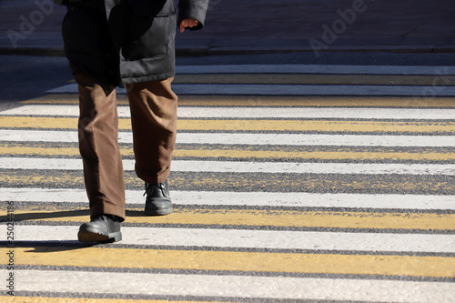 Man walking on pedestrian crossing, front view. Male legs on the crosswalk, street safety concept