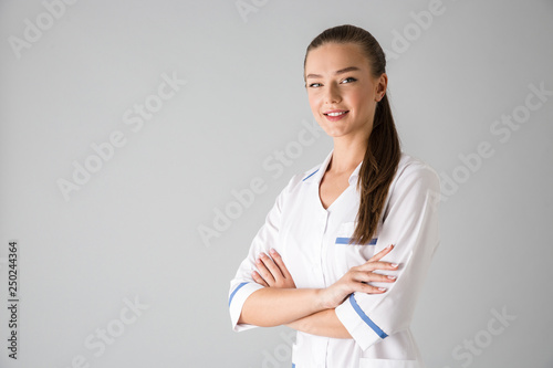 Beautiful young woman cosmetologist doctor isolated over grey wall background.