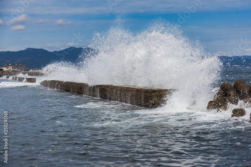 A large sea wave breaks about a breakwater. Close-up. Seascape