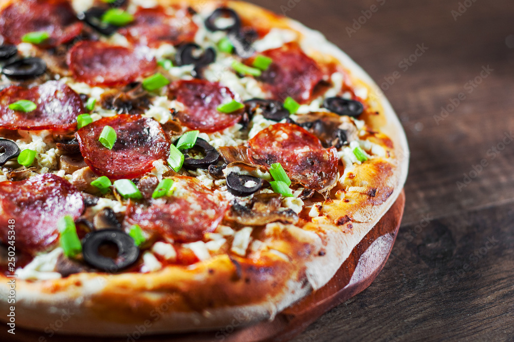 Pizza with Mozzarella cheese, salami, pepper, pepperoni, olives, Spices and mushroom. Italian pizza on wooden table background Pizza with Mozzarella cheese, salami, pepper, pepperoni, olives, Spices and mushroom. Italian pizza on wooden table background
