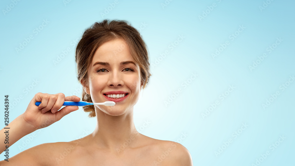 oral care, dental hygiene and people concept - smiling woman with toothbrush cleaning teeth over blue background oral care, dental hygiene and people concept - smiling woman with toothbrush cleaning teeth over blue background