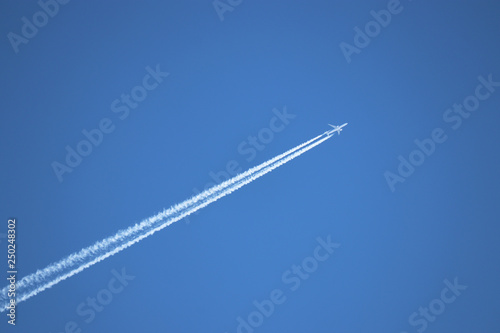 Jet airplane with contrail. Trace of the high flying plane in the clear blue sky