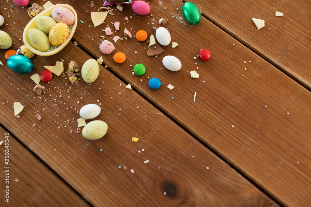 easter, sweets and confectionery concept - chocolate egg and candy drops on wooden table easter, sweets and confectionery concept - chocolate egg and candy drops on wooden table