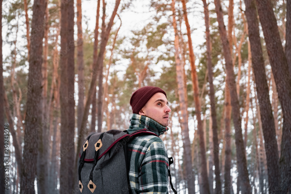 Hiking male person in winter forest. Man in checkered winter shirt walking in beautiful snowy woods Hiking male person in winter forest. Man in checkered winter shirt walking in beautiful snowy woods