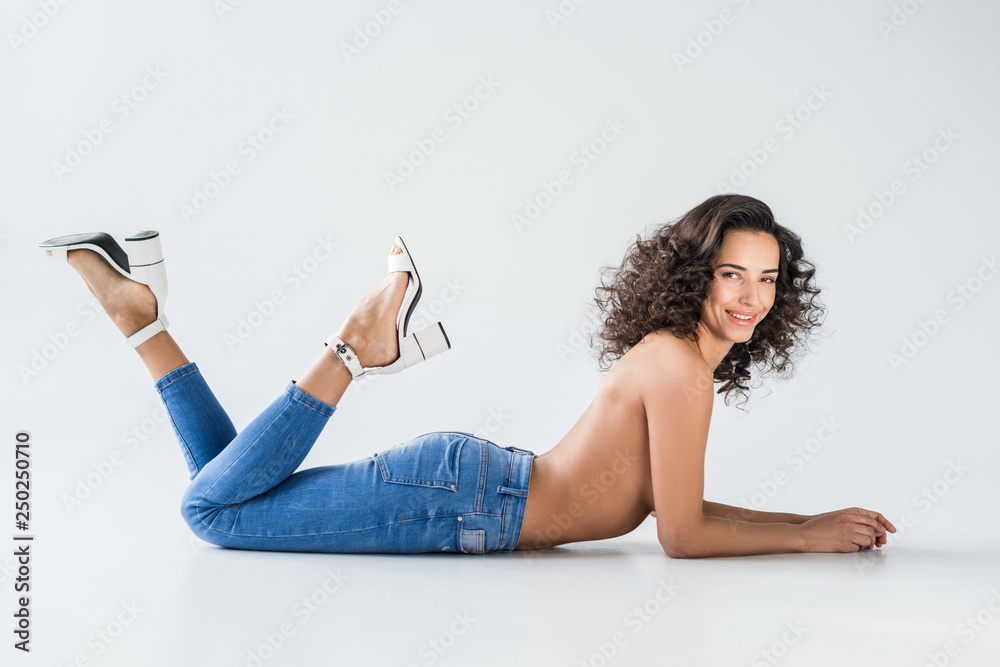 Stockfoto Sexy girl in jeans with nude breasts lying on grey background |  Adobe Stock