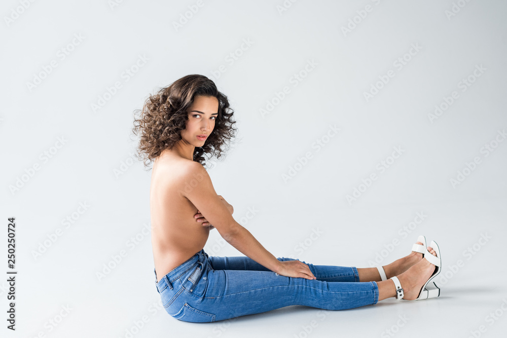 Stunning girl in jeans with nude breasts sitting on grey background Stock  Photo | Adobe Stock