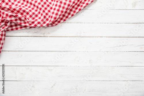 Photo Red checkered kitchen tablecloth on wooden table.