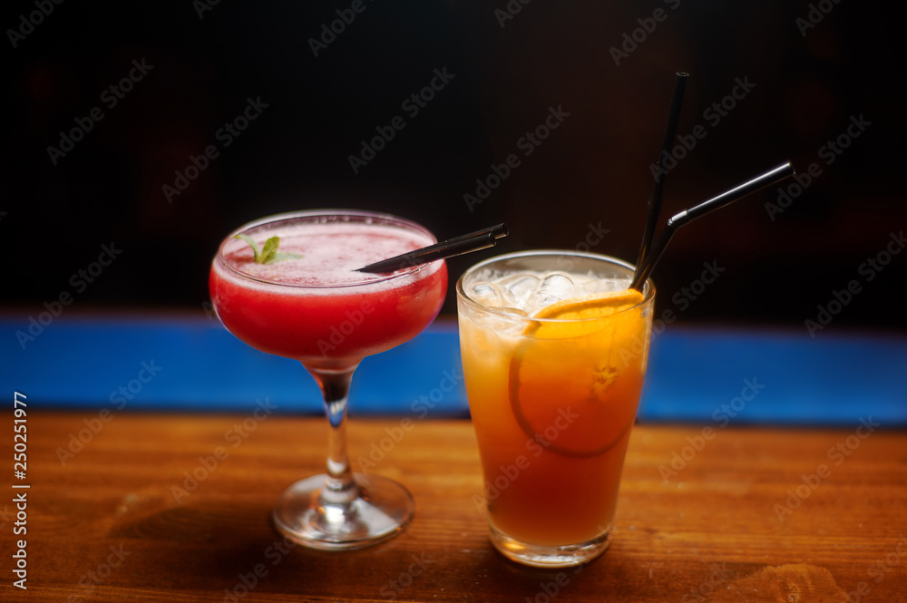 two cocktails at bar counter. red and orange drinks. two cocktails at bar counter. red and orange drinks.