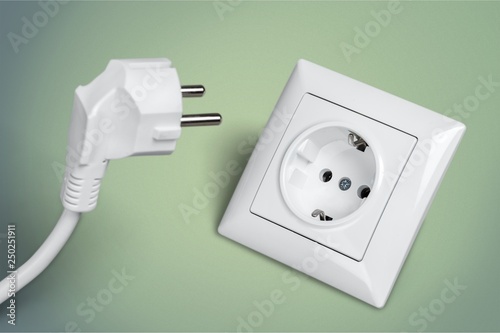 White electrical plug in the electric socket on a wall photo