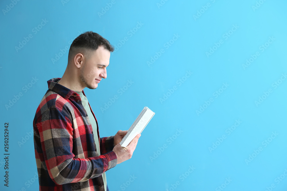 Handsome young man with book on color background Handsome young man with book on color background